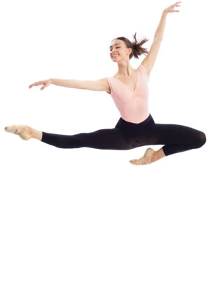 Dancer in a pink leotard and black tights performing a grand jeté with arms extended mid-air.
